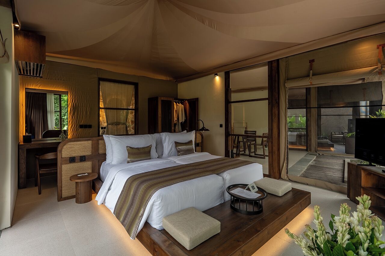 A spacious bedroom with a large bed, bedside tables, a desk, and a television.