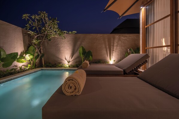 Una piscina al aire libre, sillones reclinables de piscina