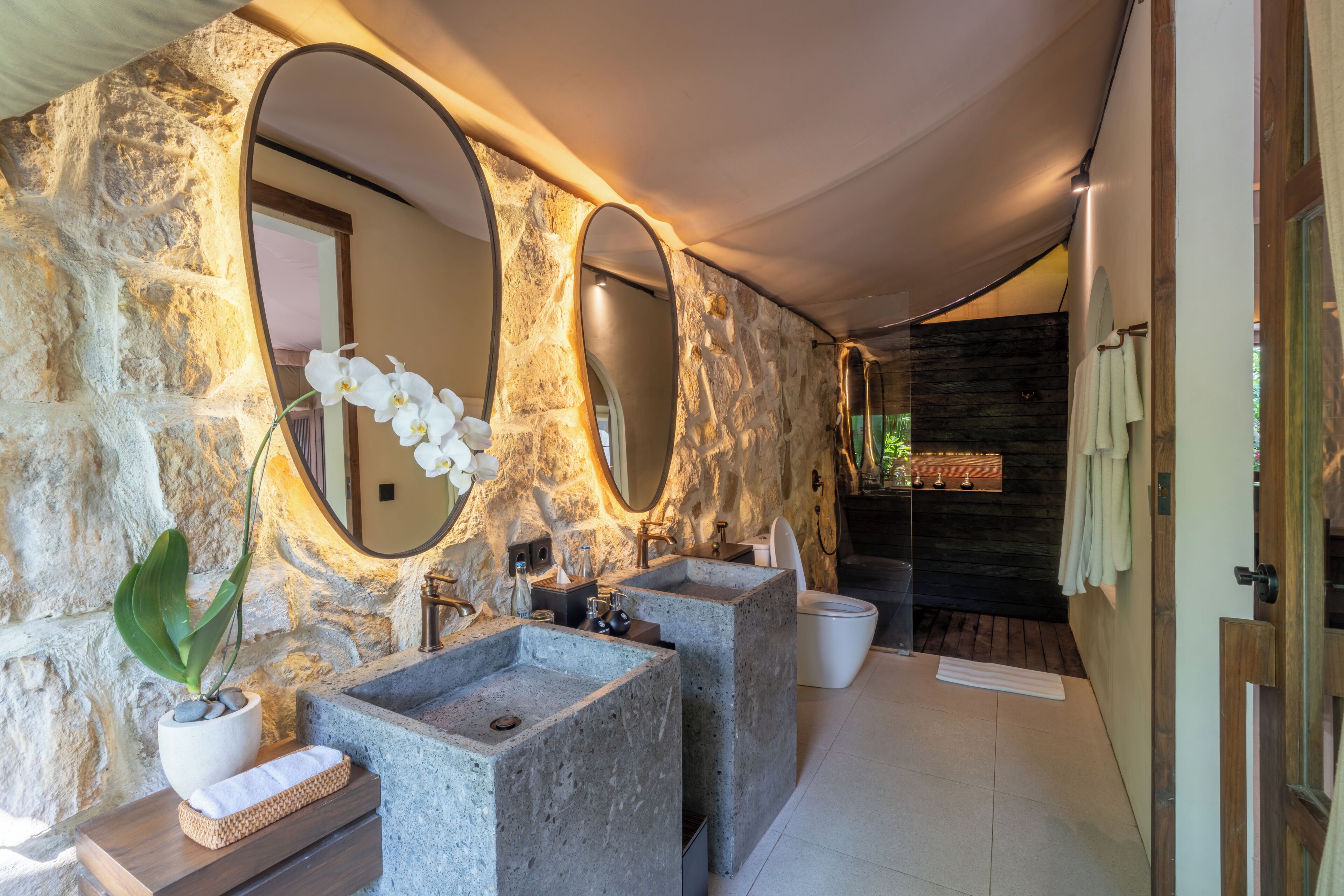 Un bagno con pareti in pietra, due lavabi e uno specchio grande.