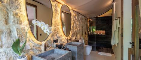Un bagno con pareti in pietra, due lavabi e uno specchio grande.