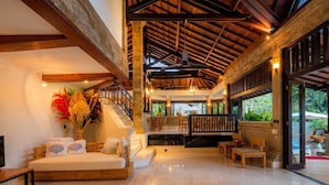 A spacious lobby with a high ceiling, a staircase, and a seating area with a view of the outdoors. - Villa Frangipani Seminyak (Seminyak)