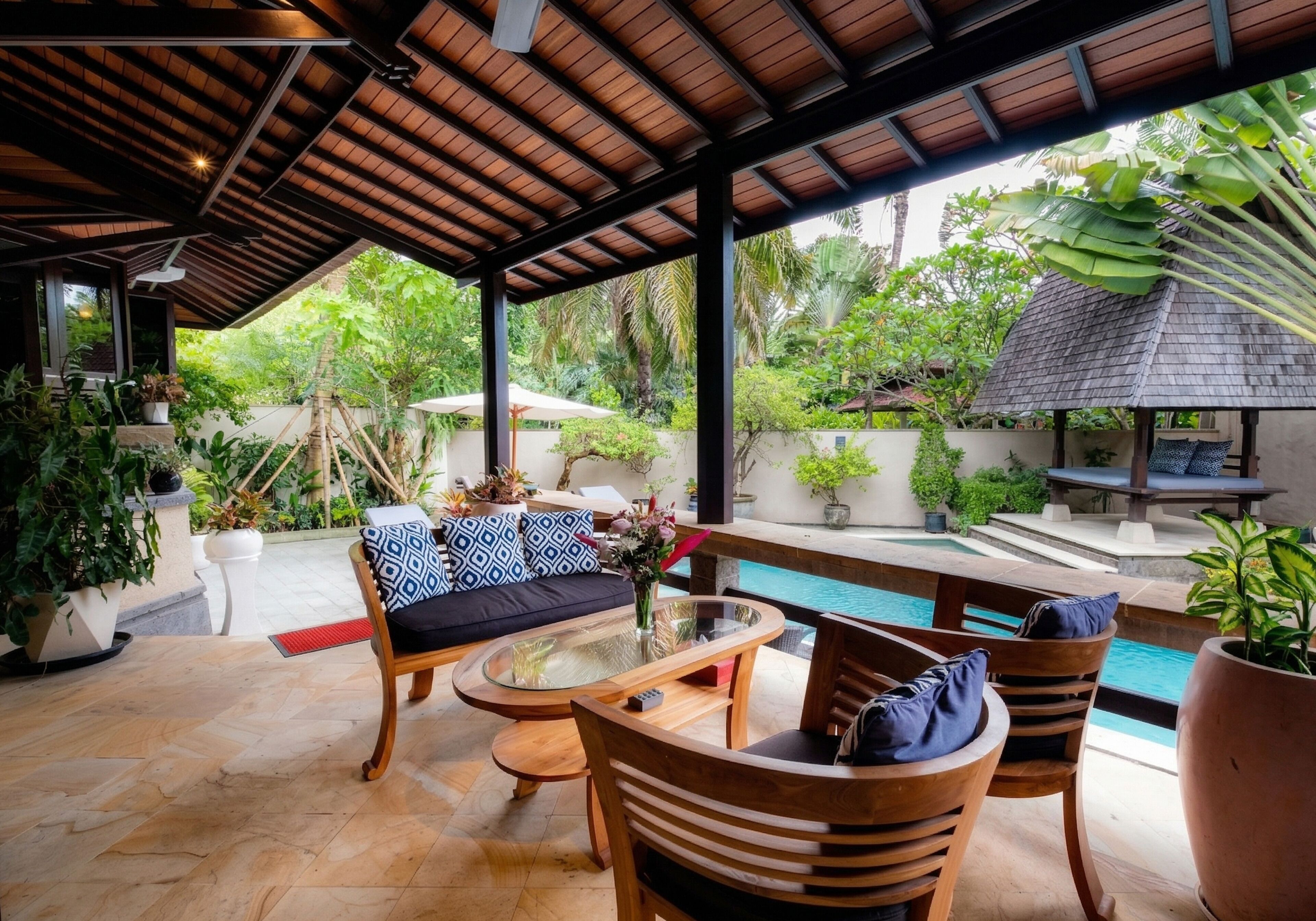 An outdoor seating area with a pool, wooden furniture, and potted plants.