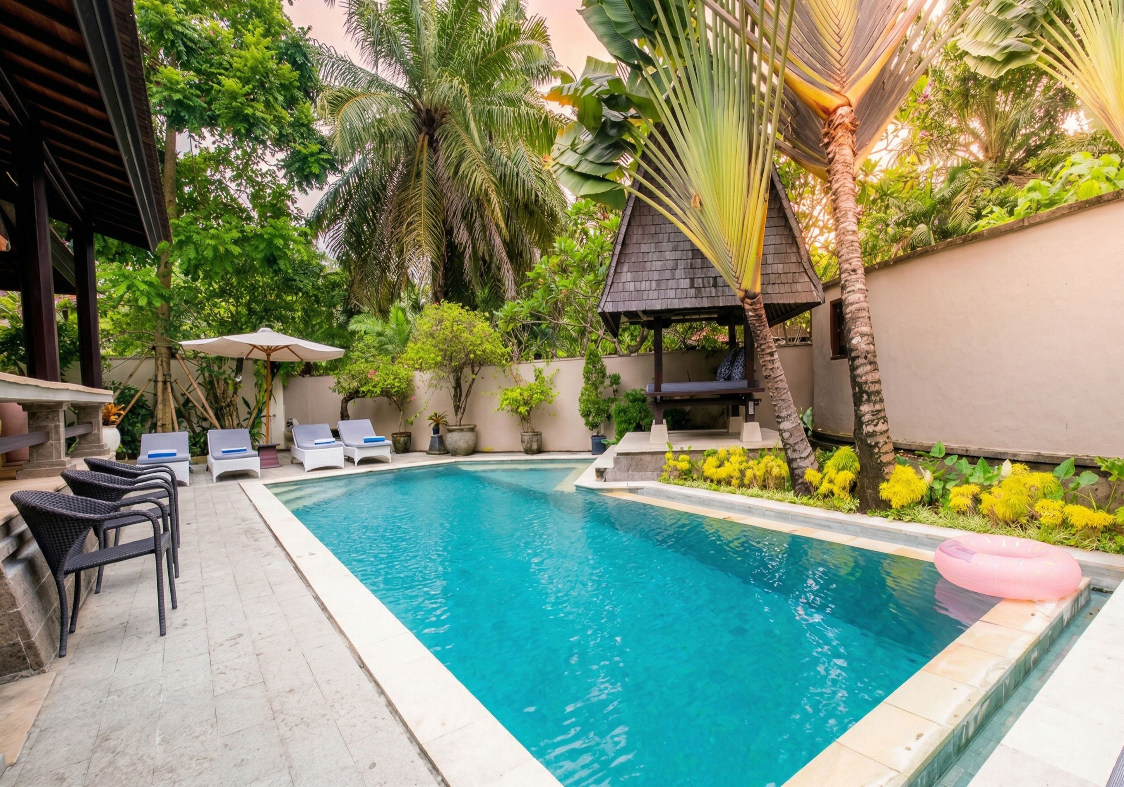Une piscine dotée de chaises longues, d’une pergola et de plantes tropicales.
