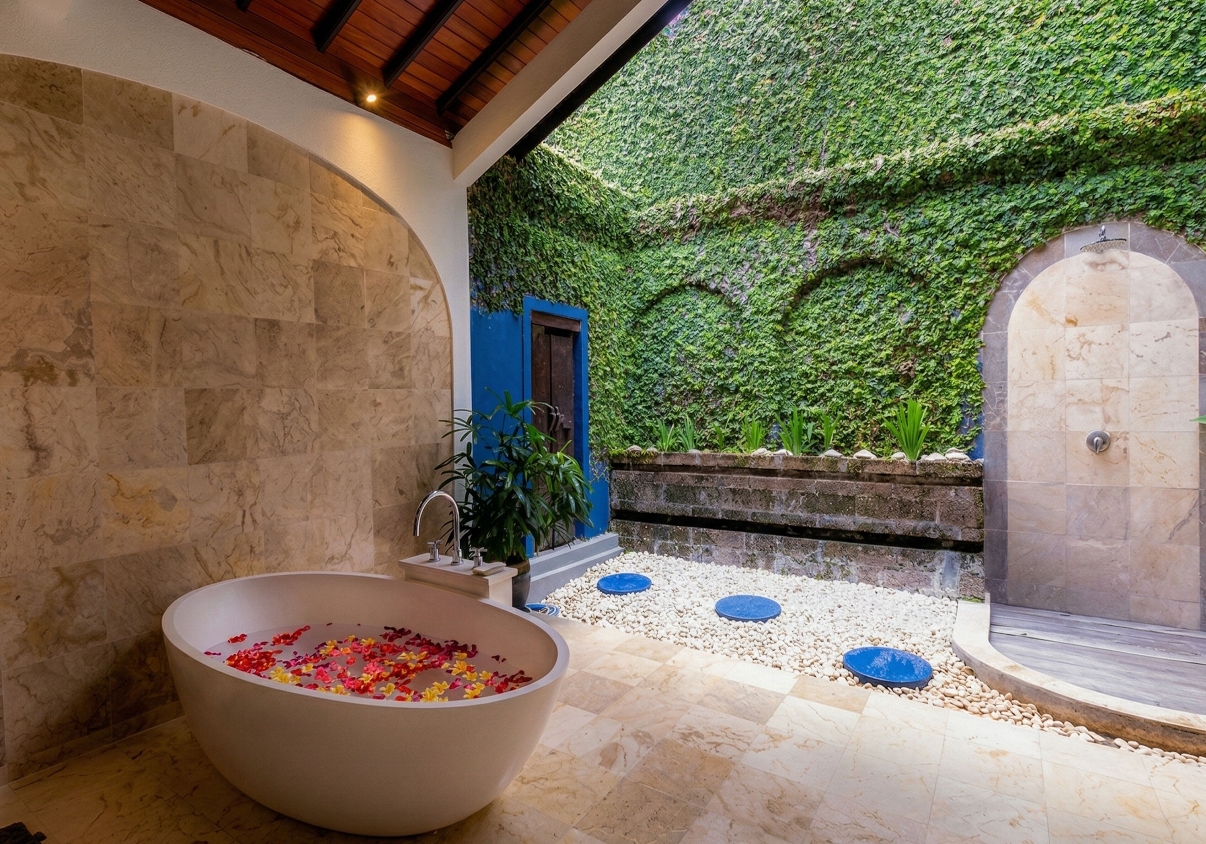 A spa area with a large bathtub, a shower, and a wall covered in greenery.