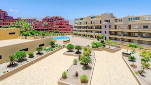 A hotel courtyard with a swimming pool, multiple balconies, and various plants. - La Perla by Interhome (El Médano)