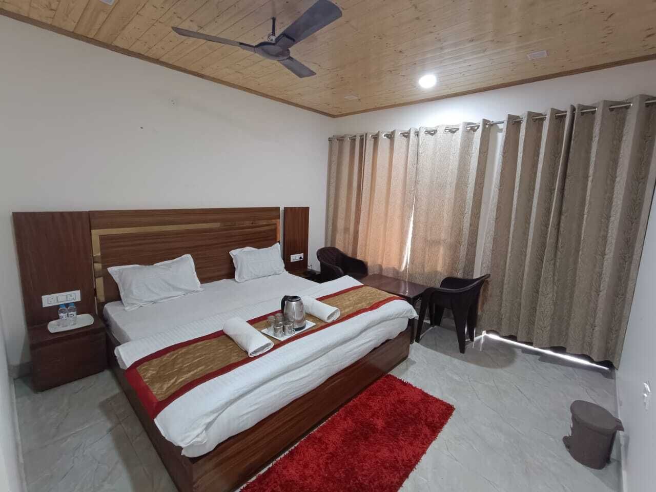 Una habitación de hotel con una cama de madera, una alfombra roja, un escritorio y una silla.