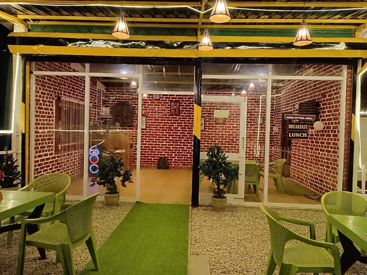 A restaurant with brick walls, green chairs, and a green carpet.