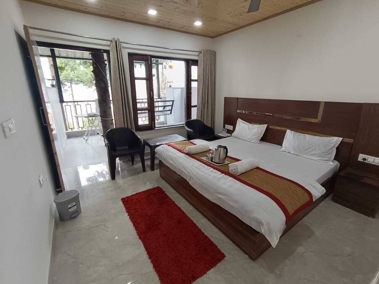 Een hotelkamer met een groot bed, een bureau en een stoel. Er is een schuifdeur die leidt naar een buitenruimte.
