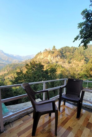 A balcony with two chairs overlooking a mountainous landscape. - Abodes Elegant Hills (Dehradun)