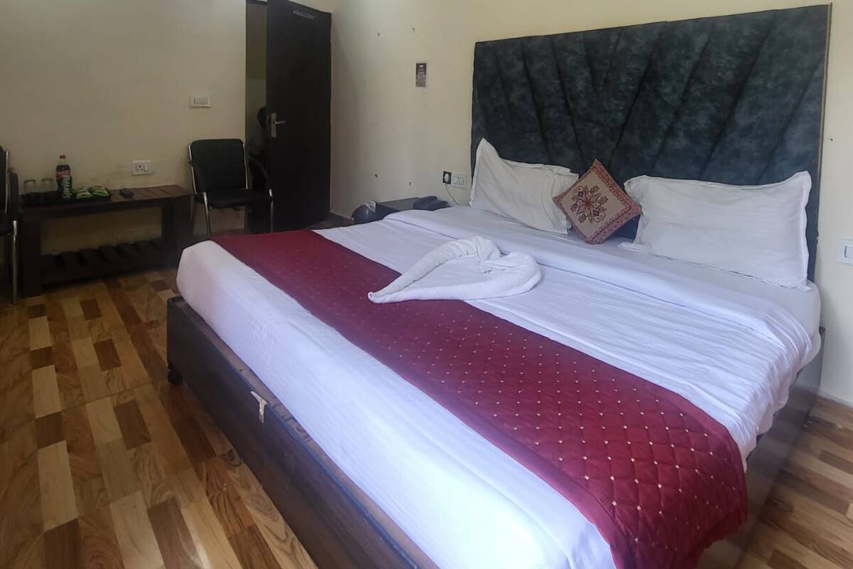 Une chambre d’hôtel avec un lit, un bureau, une chaise, un ventilateur de plafond et une porte.