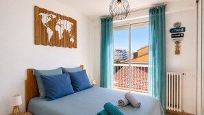 Ein Schlafzimmer mit Bett, Kissen, einer Weltkarte, einem Fenster mit Vorhängen, einer Heizung und einem Hinweisschild auf einen Ort.