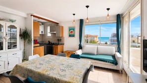 A modern apartment with a kitchen, dining area, and a sofa by a large window overlooking the sea. - Brise Marine • A Seaside Escape in Palavas (Palavas-les-Flots)