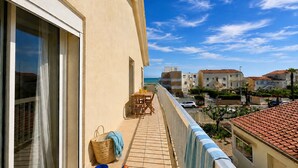 Ein Balkon mit Tisch, Stühlen, einem Korb und Blick auf den Strand.