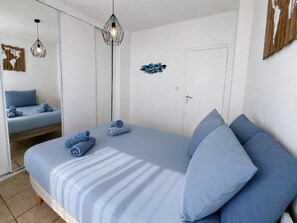 Un dormitorio con una cama, dos mesitas de noche, un armario y un espejo.