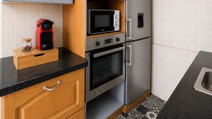 Eine kleine Küche mit Mikrowelle, Backofen und Kühlschrank.