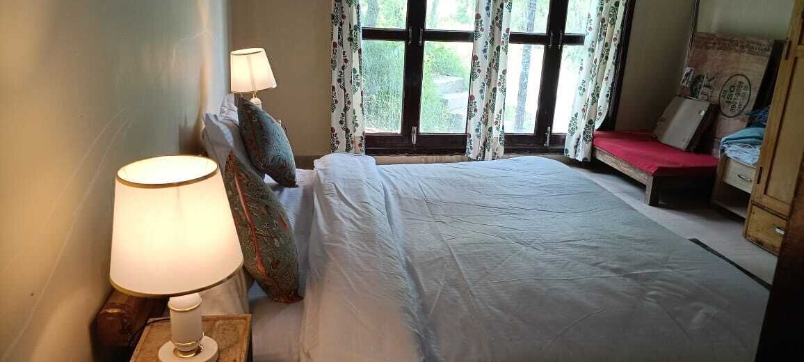 Une chambre à coucher avec un lit, deux lampes de chevet, une fenêtre avec des rideaux et un petit bureau avec une chaise.