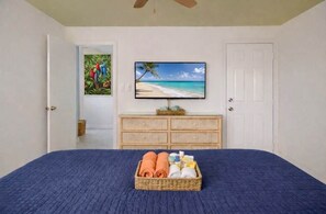 Una camera da letto con un letto, una televisione a parete, un comò e una porta.