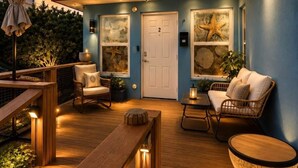 A wooden deck with outdoor furniture, a white door, and starfish artwork on the walls.