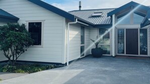 A modern house with a covered patio, a small garden, and a large window.