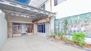 Un edificio con un acceso cubierto, un mural en la pared y una pequeña zona ajardinada.