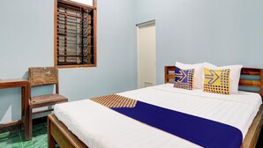 Un dormitorio con cama de madera, colcha azul y almohadas estampadas.