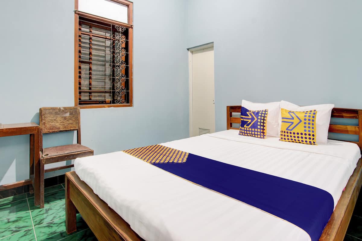 Un dormitorio con cama de madera, colcha azul y almohadas estampadas.