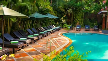 Alberca al aire libre, sombrillas en la alberca y camastros