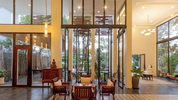 A spacious indoor area with wooden furniture, large windows, and a patterned floor. - YASODHARAPURA RESIDENCE (Siem Reap)