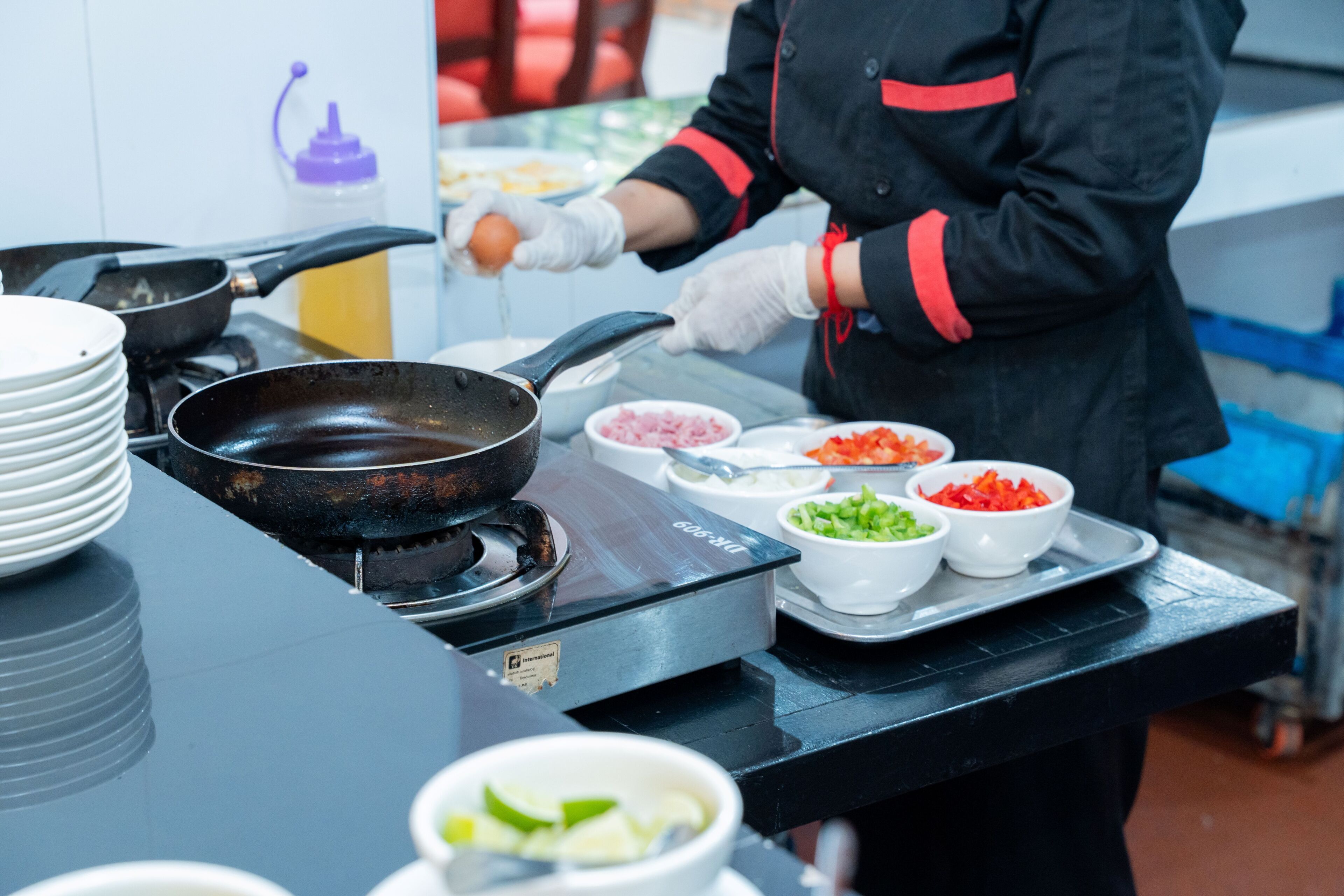 Una cocina con estufa, sartén y varios cuencos con comida.
