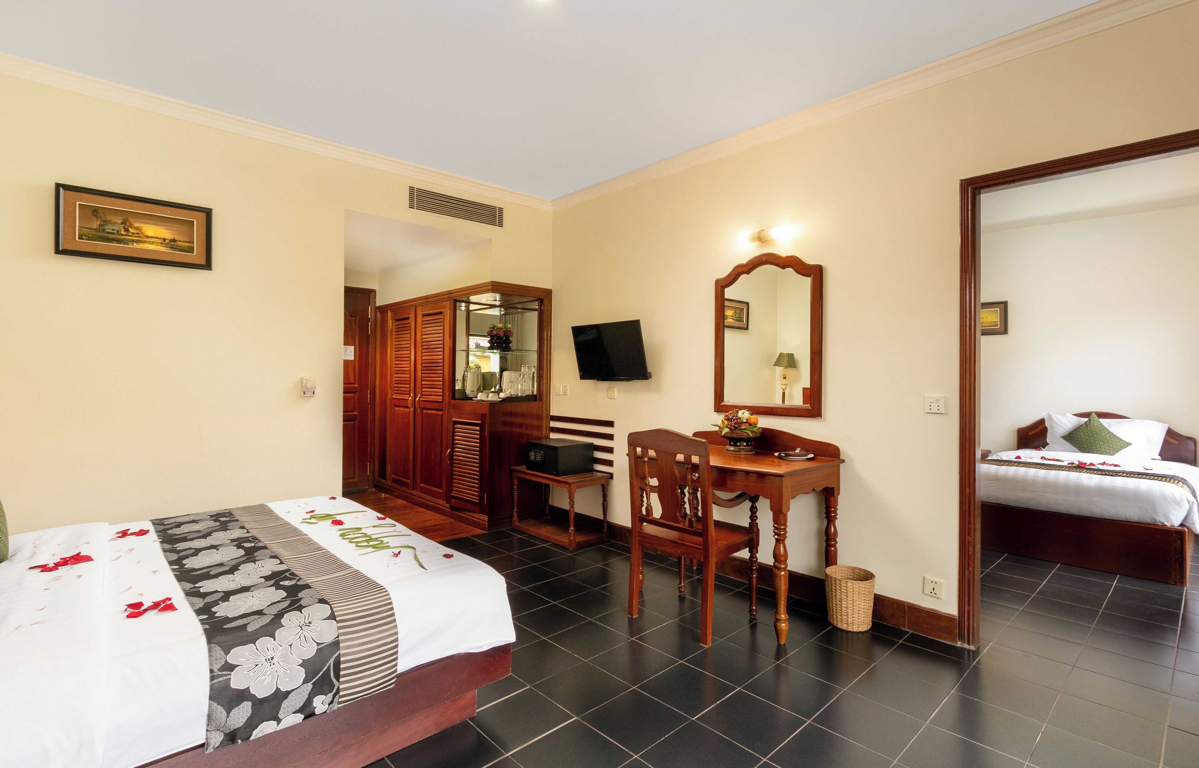 A hotel room with a bed, a desk with a chair, a television, and a mirror.
