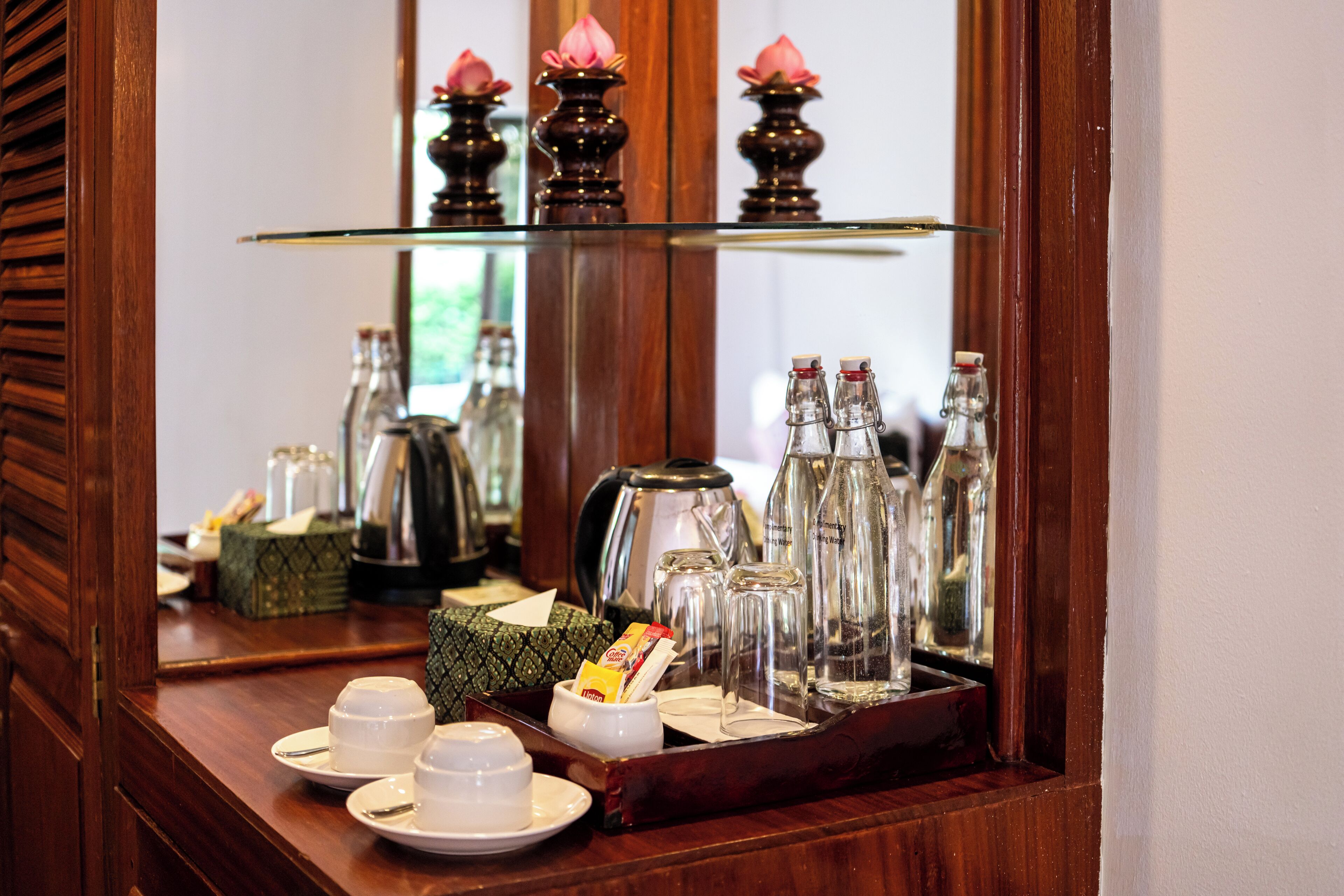 A breakfast tray with tea cups, a teapot, sugar cubes, and a box of tea bags on a wooden table.