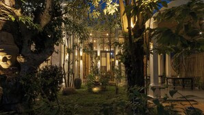 An outdoor garden area with a seating area and a building in the background. - YASODHARAPURA RESIDENCE (Siem Reap)