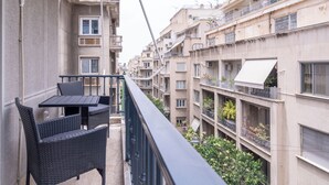 A balcony with a table and chairs, overlooking a row of multi-story residential buildings. - Urban Elegance in Kolonaki 7min walk to Syntagma (Athina)