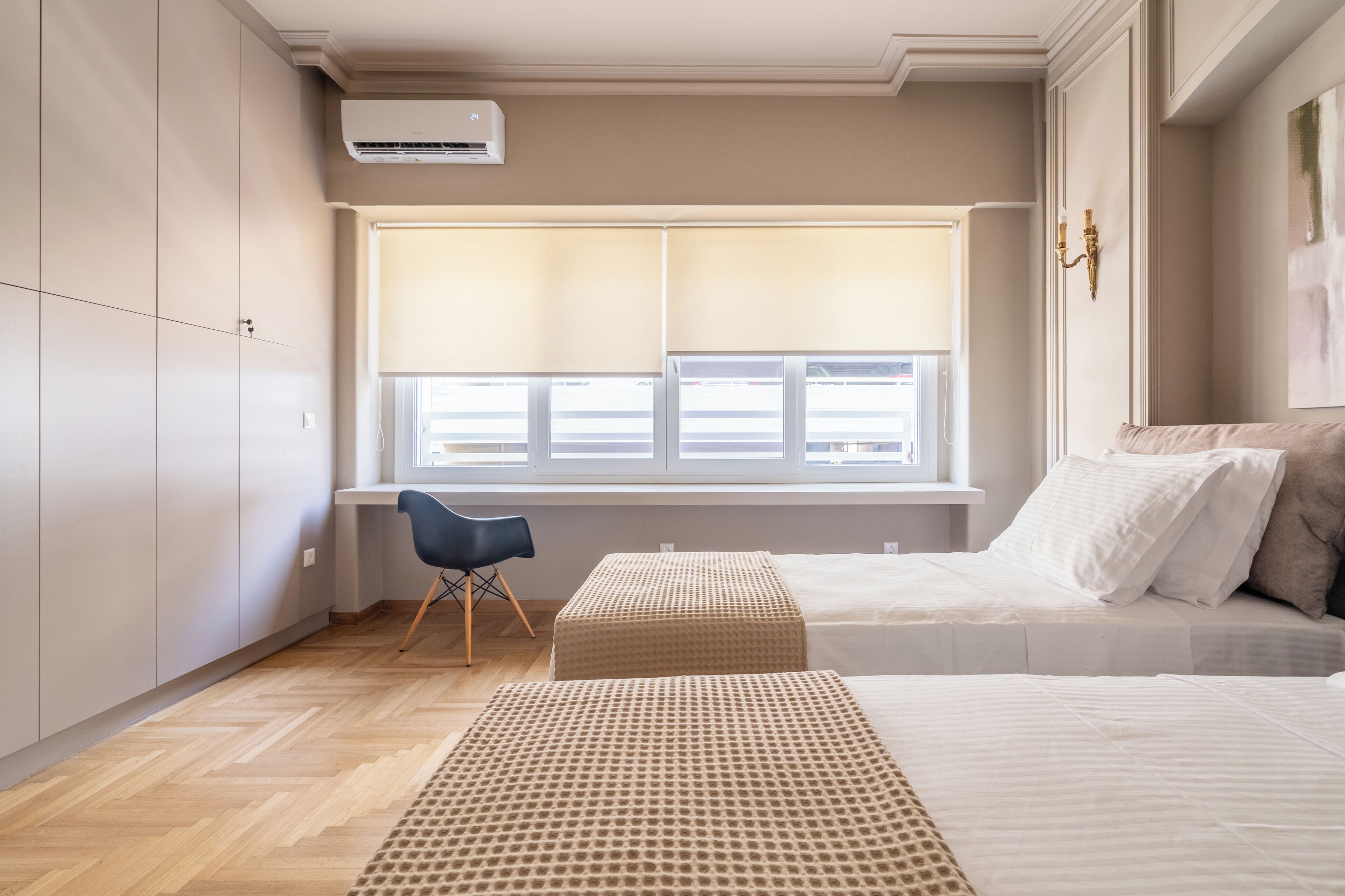 A bedroom with a large window, a desk, and a chair.