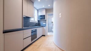 A modern kitchen with black countertops, stainless steel appliances, and light wood flooring. - Urban Elegance in Kolonaki 7min walk to Syntagma (Athina)
