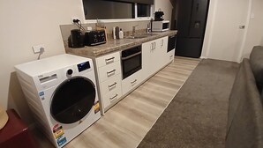 Eine kompakte Küche mit Waschmaschine, Mikrowelle, Backofen und einer kleinen Arbeitsplatte.