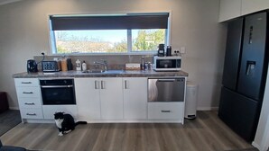 Eine moderne Küche mit weißen Schränken, einem Edelstahl-Geschirrspüler, einem schwarzen Kühlschrank, einer Mikrowelle und einer Kaffeemaschine.