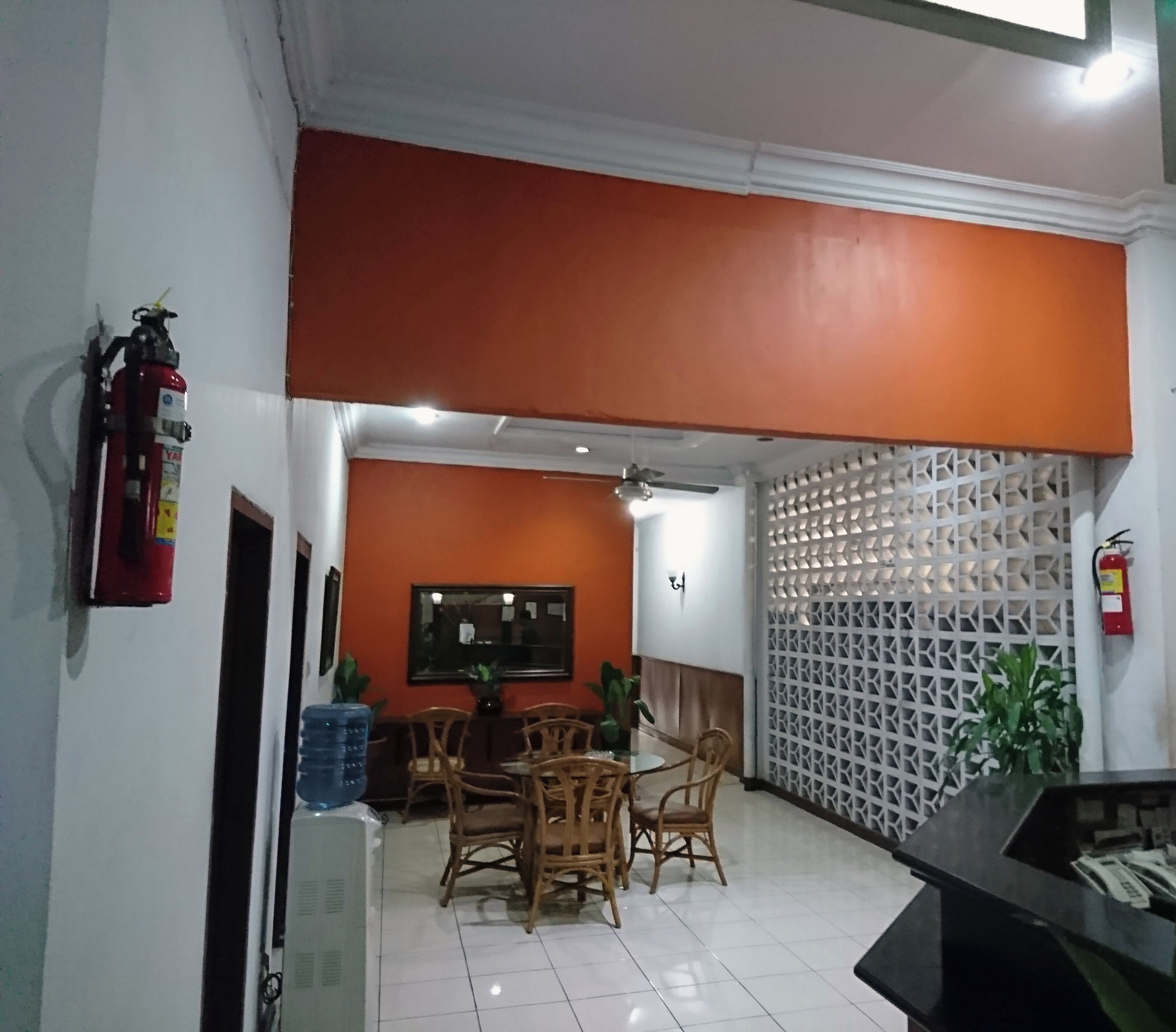 A dining area with a table and chairs, a fire extinguisher, and a decorative wall.