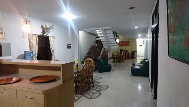 A spacious living area with a staircase, a dining table with chairs, and a sofa. - Wisma Shalom  (Jakarta)