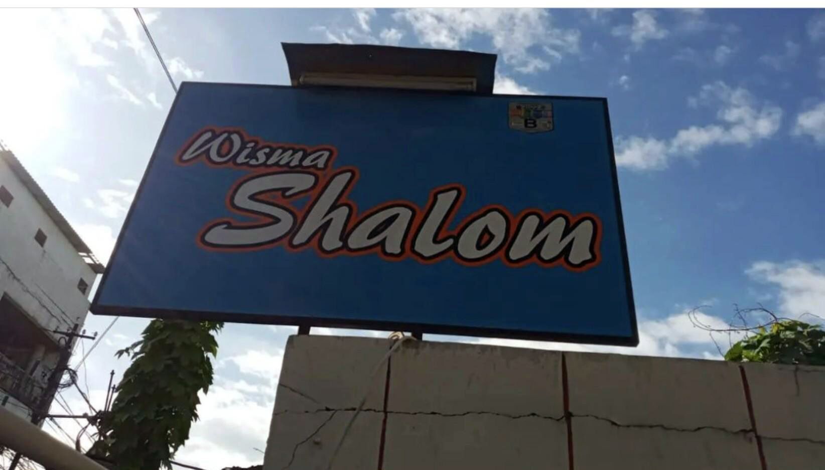 Une enseigne portant le nom « Wisma Shalom » sur un fond bleu.