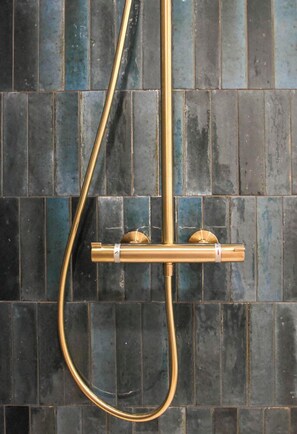 A shower with a gold hose and a horizontal bar.