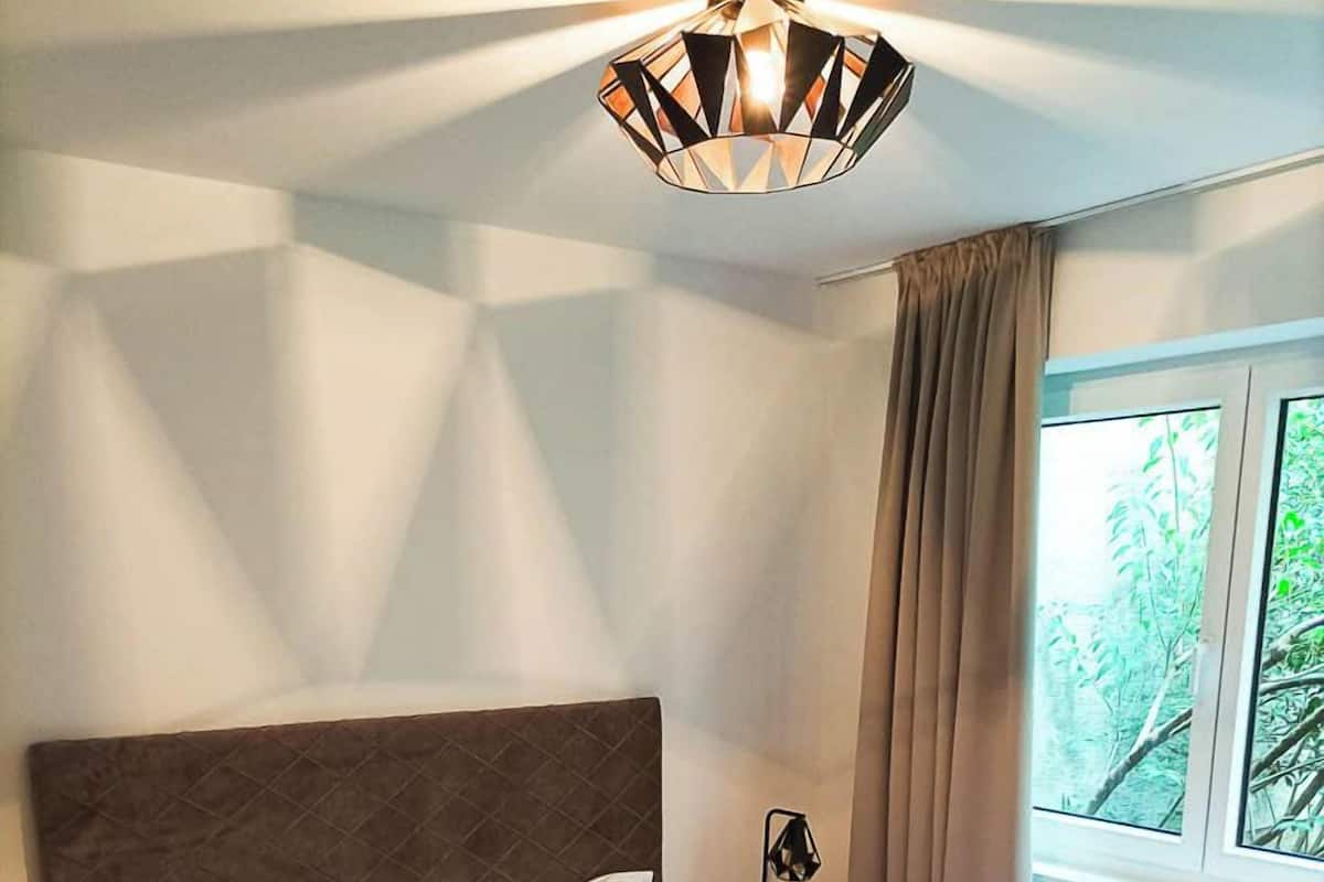 A neatly made bed with white linens, a quilted headboard, and a bedside lamp.