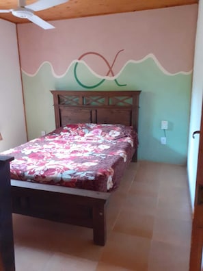 A bedroom with a bed, wooden headboard, and a ceiling fan.