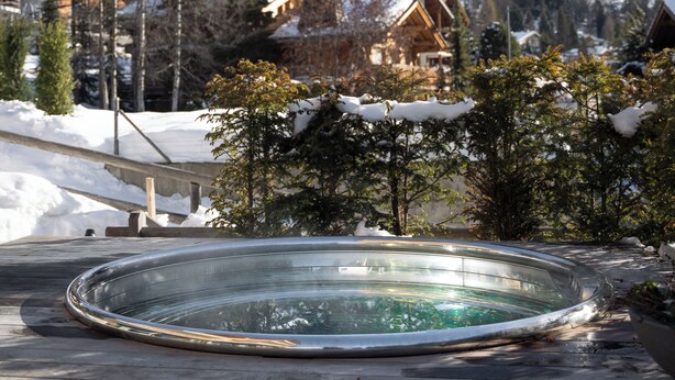 A snow-covered mountain landscape with wooden chalets and a clear swimming pool in the foreground. - No.14 Verbier (Bagnes)