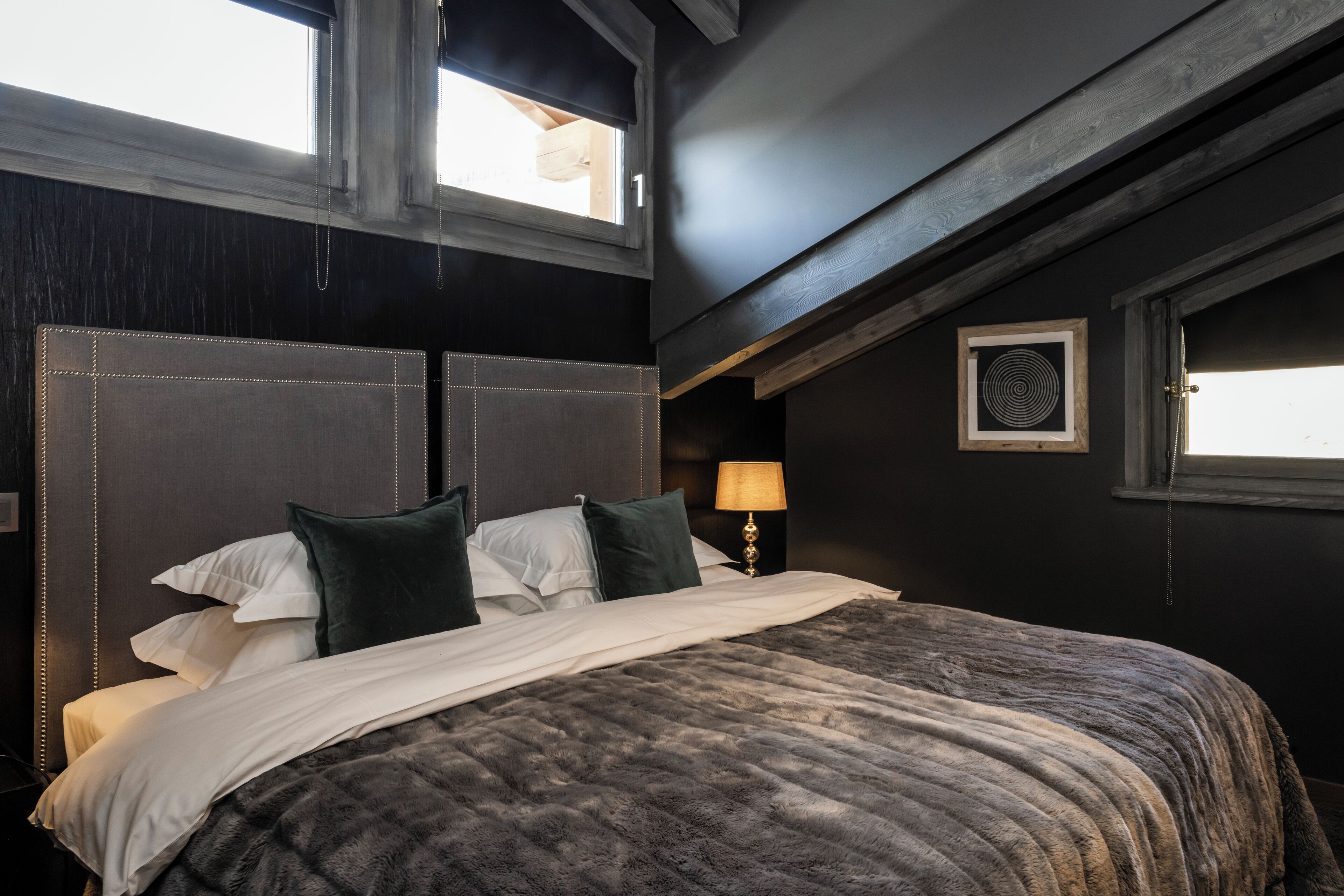 A bedroom with a large bed, dark walls, and a window.