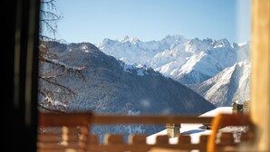 A mountain view through a window with a wooden railing. - No.14 Verbier (Bagnes)