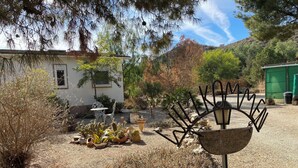 A garden with cacti, a metal sculpture, and a white building with a window. - Tolles Ferienhaus in Südspanien, in Ruhiger Natur zum Entspannen und Wandern (Águilas)