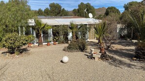 A house with a solar panel roof, surrounded by various potted plants and a gravel driveway. - Tolles Ferienhaus in Südspanien, in Ruhiger Natur zum Entspannen und Wandern (Águilas)