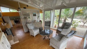 A spacious patio area with wicker furniture, a glass table, and a view of the garden through large windows. - Tolles Ferienhaus in Südspanien, in Ruhiger Natur zum Entspannen und Wandern (Águilas)