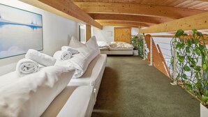 A cozy, wooden-floored room with a bed, a bench with towels, a painting, and a potted plant. - Casa Hermi by Interhome (Churwalden)
